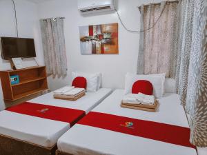 two beds in a room with red and white at MKB Pension in Coron