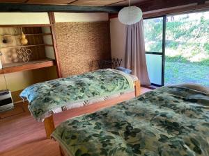 two beds in a room with a large window at KOMINKA guest house in Omachi