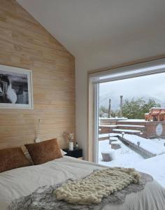 a bedroom with a bed and a large window at Confortable refugio de monataña con vista al Volcan in Malalcahuello