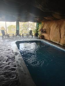 una piscina in una parete di roccia con sedie intorno di Hostal familiar Bajo las estrellas a Chame