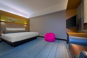 a bedroom with a bed and a pink chair at Aloft Kuala Lumpur Sentral in Kuala Lumpur