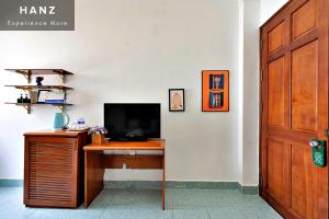 a room with a desk with a television and a door at HANZ Hotel upstair MPChill in Ho Chi Minh City