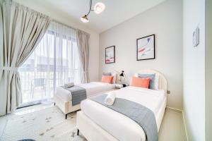 two beds in a room with a window at Damac Hills ll - 4 bedrooms House with Private Pool at Dubai Land in Dubai