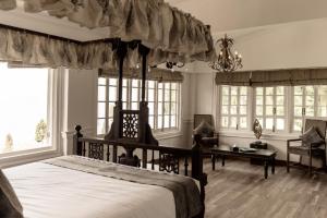 a bedroom with a canopy bed and a desk at Chhota Haazri, By The Rajbari Bawali in Darjeeling