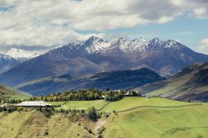 una granja en un campo con montañas en el fondo en Mahu Whenua, en Wanaka