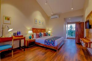 a bedroom with a bed and a desk and a window at Ananyamaya nature lodge in Khilchipur