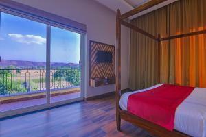 a bedroom with a bed and a large window at Ananyamaya nature lodge in Khilchipur