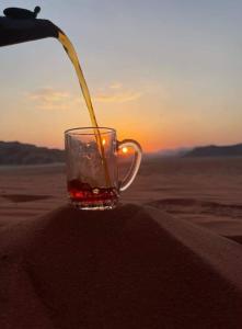 uma bebida está sendo derramada em um copo no deserto em Wadi Rum Sights Camp em Wadi Rum