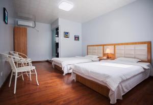 um quarto com duas camas e uma cadeira. em Pacific Islander Inn em Garapan