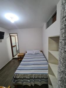 ein Schlafzimmer mit einem Bett mit einer blau-weißen gestreiften Decke in der Unterkunft LIRI House in Oxapampa