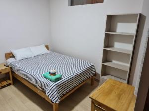 a small bedroom with a bed and a book shelf at LIRI House in Oxapampa