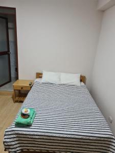 ein Bett mit blauer und weißer gestreifter Bettwäsche und einem Teller darauf in der Unterkunft LIRI House in Oxapampa
