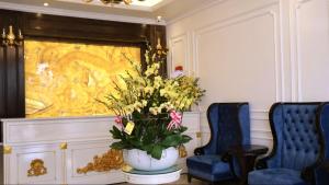 a vase of flowers on a table next to two chairs at Royal Hotel Thanh Trì in Hanoi