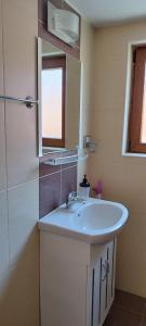a bathroom with a white sink and a mirror at Anchors Guest House in Sozopol