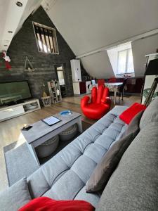 a living room with a gray couch and red chairs at Gîte Vallée de Munster chez Flavie & Ludo in Muhlbach-sur-Munster