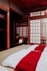 Teradaya Osaka Ryokan 150m2 寺田屋大阪旅館 your own property sweet home in Osaka في أوساكا: سرير احمر وبيض في غرفة بها نوافذ