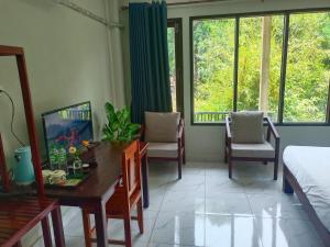 a bedroom with a desk and chairs and windows at Vang Vieng Champa Hotel in Vang Vieng