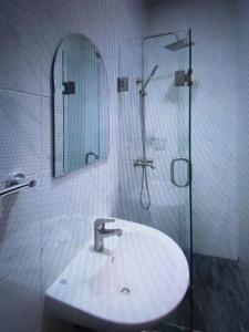 y baño con lavabo y ducha con espejo. en Light house hotel and apartments Lekki phase 1, en Lekki