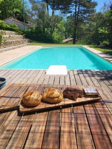 dos panes en una mesa de madera junto a una piscina en Lou mas del ranc, en Roquestéron