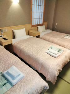 ein Zimmer mit 3 Betten und Handtüchern darauf in der Unterkunft Hotel Hanakomichi in Nara