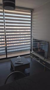 sala de estar con TV y mesa frente a una ventana en Arriendo de departamento por día en Santiago