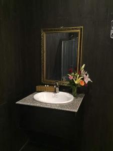 um lavatório de casa de banho com um espelho e um vaso de flores em RUBY Cà Mau em Cà Mau