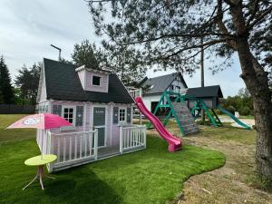 a pink play house with a slide and a playground at Domki wypoczynkowe LAS in Śliwice