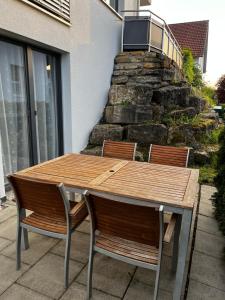 drewniany stół z krzesłami i kamienną ścianą w obiekcie Schönes Apartment mit Terrasse w mieście Waldstetten