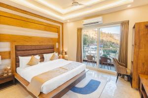 a bedroom with a large bed and a balcony at Stone Wood Hotel, Rishikesh in Rishīkesh