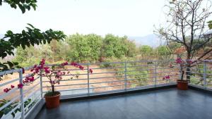 un balcón con flores rosas en macetas sobre una barandilla en Aum Villa Pet Friendly, en Karjat