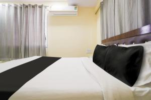 a bedroom with a black and white bed and a window at OYO Hotel Bluebird Inn in Nagpur