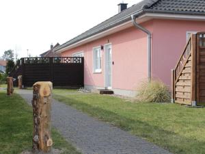 Boddensurfer 3a في Pruchten: منزل وردي مع بوابة وسياج
