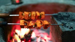a row of food on a stick over a fire at Aum Villa Pet Friendly in Karjat