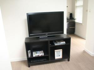 a flat screen tv on a black entertainment center at Muijs Comfortable holiday residence in Huisduinen