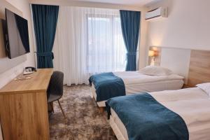 a hotel room with two beds and a desk at Hotel Regal in Braşov