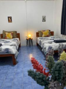 a room with two beds and a table with a lamp at Colibri Inn in Thongsala