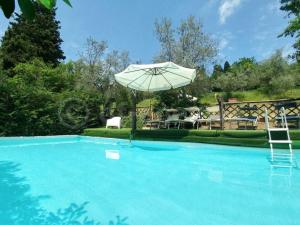 una gran piscina azul con sombrilla y sillas en Historic villa near Florence, en Rignano sullʼArno