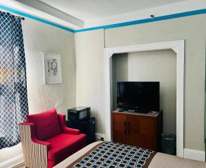 a room with a bed and a red chair and a television at Admiral Hotel in San Francisco