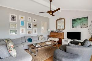 uma sala de estar com um sofá e duas cadeiras e uma televisão em Stylish Beach Home - Moments from Water em Terrigal