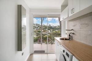 a kitchen with a view of a balcony at Stylish Beach Home - Moments from Water in Terrigal
