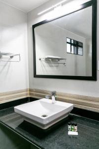 bagno con lavandino bianco e grande specchio di Aloha Holiday Resort a Baga