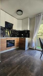 a kitchen with white cabinets and a large window at Apartament Słoneczna Wydma in Ustka
