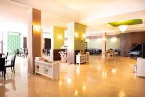 a large lobby with tables and chairs and a piano at Hotel Ambasador Mamaia in Mamaia