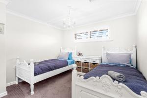een witte slaapkamer met 2 bedden en een kroonluchter bij 56 Picture Perfect Applecross 5br 3bth in Perth
