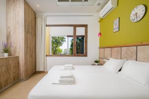 a bedroom with a large white bed and a window at More Crete Village House Koutouloufari in Hersonissos