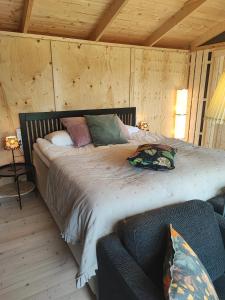 1 dormitorio con cama con almohadas y sofá en Sjugare Gård Glamping, en Leksand