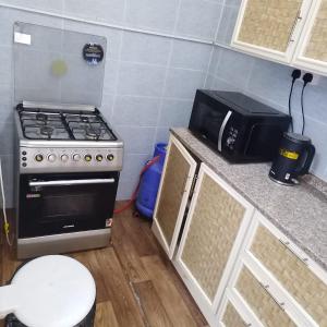 een keuken met een fornuis en een magnetron bij العين الهيلي مصباح ب 9 in Al Ain