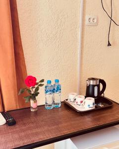 a table with bottles of water and cups and a coffee maker at Green Flower Hotel in Kutaisi