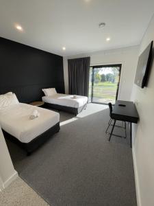 a hotel room with two beds and a desk at Harden Country Club Motel in Harden