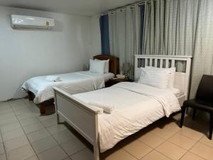 a hotel room with two beds and a chair at Many Trees in Bangkok